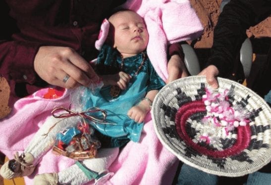 A Navajo baby during the First Laugh Party, giving gifts to family.