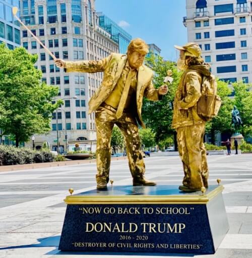 Living statue of Trump sending child back to school in a mask.