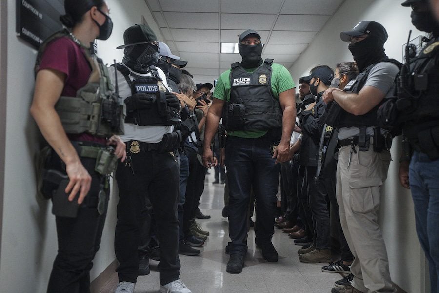 Masked ICE agents wait for migrants at immigration court